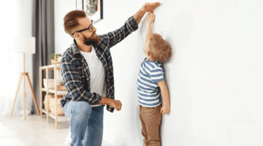 concept of development, growing up. a father measures height of his young child son